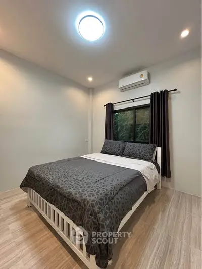Cozy bedroom with modern decor and large window offering natural light.