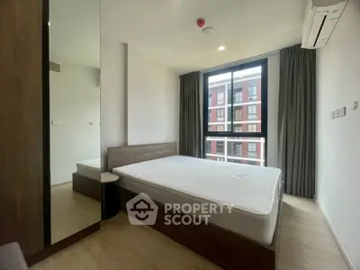 Modern bedroom with large window and minimalist design in urban apartment.