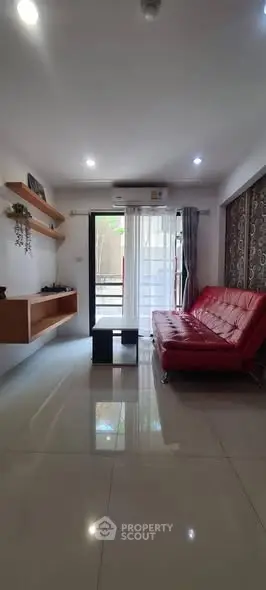 Modern living room with red sofa and sleek decor, featuring large windows for natural light.