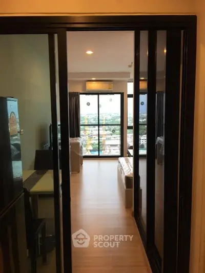 Modern apartment interior with sliding glass doors and city view balcony.