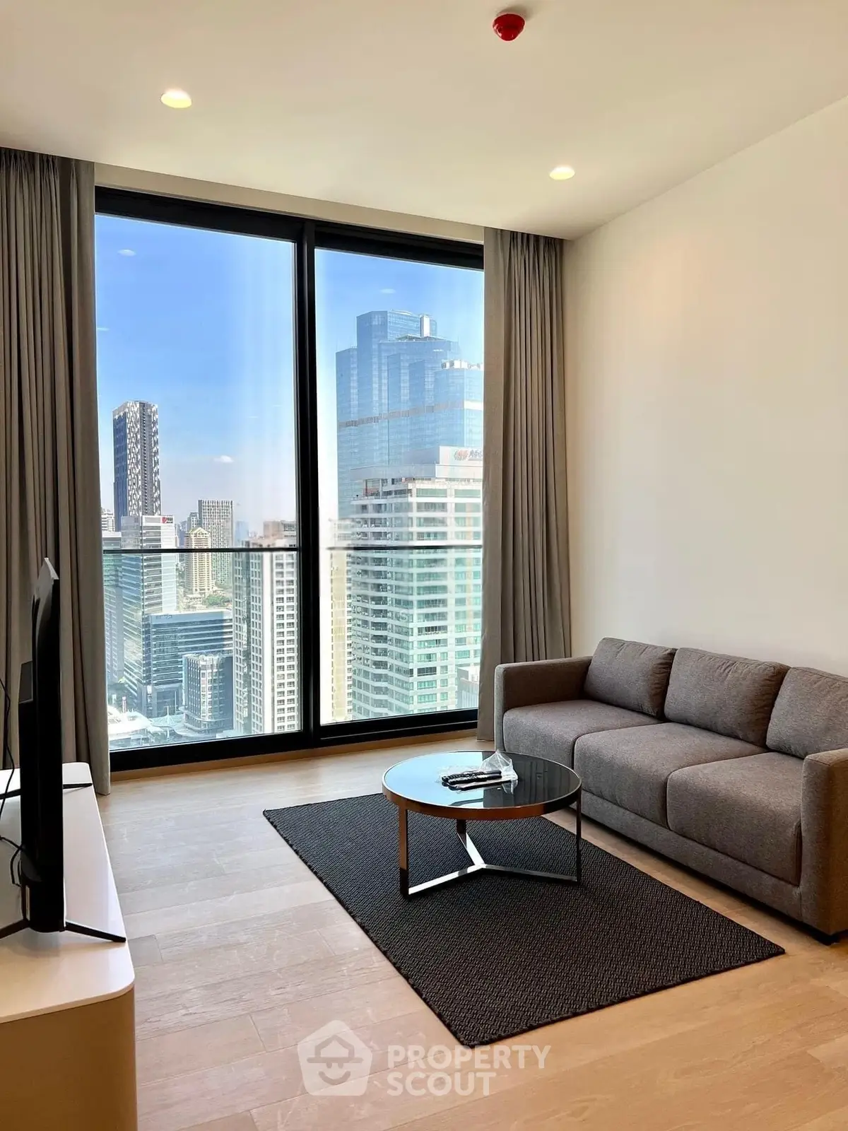 Modern living room with stunning city view, featuring sleek furniture and floor-to-ceiling windows.