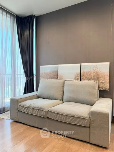 Modern living room with cozy gray sofa and large window offering natural light and scenic view.