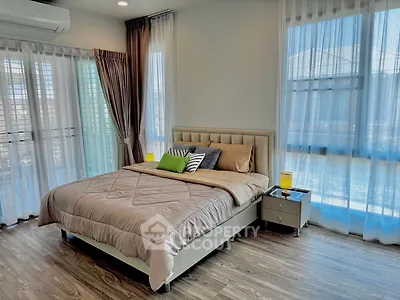 Spacious bedroom with modern decor and large windows for natural light.