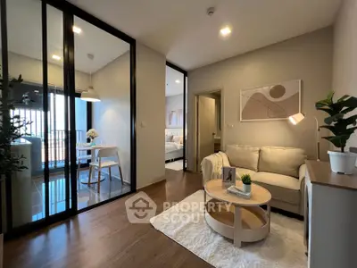 Modern living room with cozy seating and stylish decor, adjacent to a dining area with balcony access.