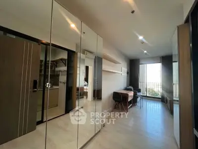 Modern apartment interior with mirrored closet and open living area leading to balcony.