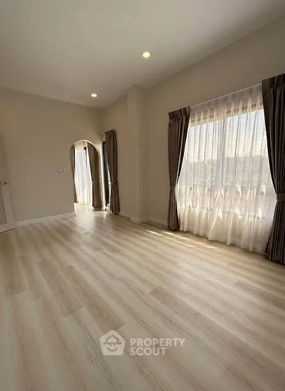 Spacious empty room with large windows and elegant curtains, perfect for customization.