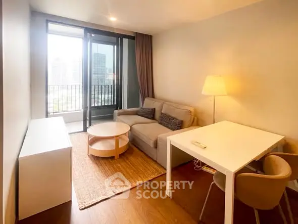 Modern living room with cozy sofa, stylish table, and city view balcony in a high-rise apartment.