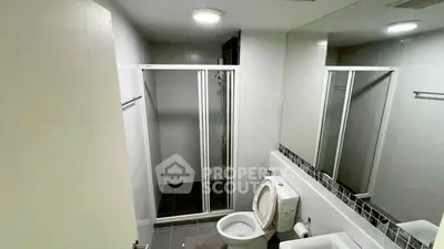 Modern bathroom with sleek shower and white fixtures in a contemporary apartment.