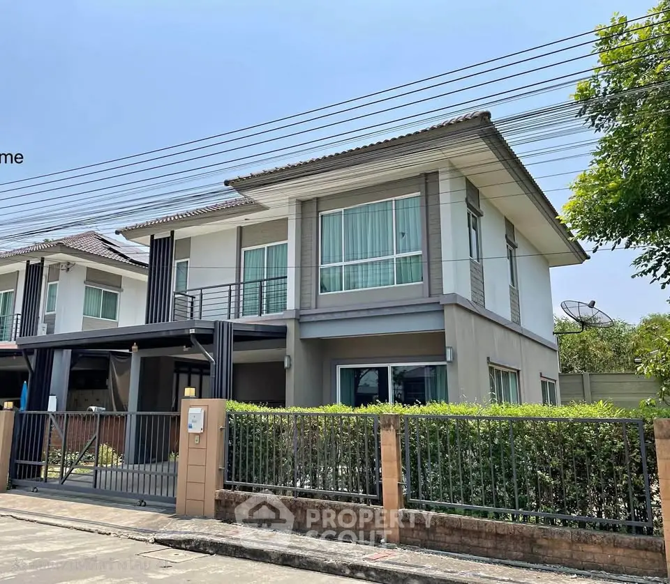 Modern two-story house with large windows and gated driveway in a suburban neighborhood.