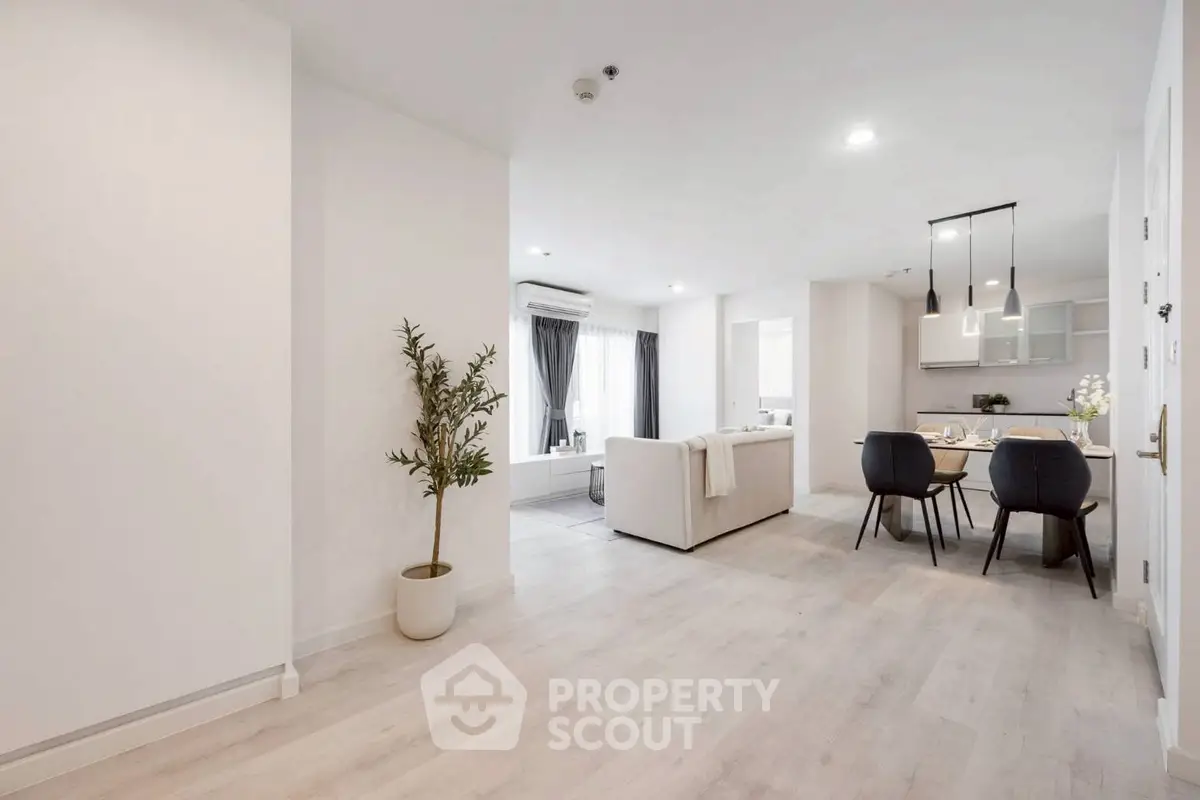 Spacious modern living room with open kitchen and dining area, featuring elegant decor and natural light.