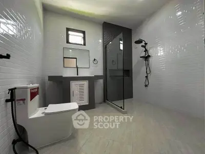 Spacious modern bathroom with sleek fixtures and glass shower enclosure.