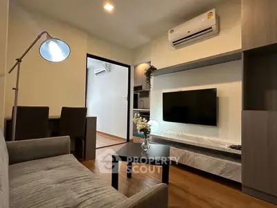 Modern living room with sleek furniture and wall-mounted TV in cozy apartment.