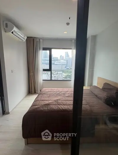 Modern bedroom with city view, featuring a large bed and air conditioning, ideal for urban living.