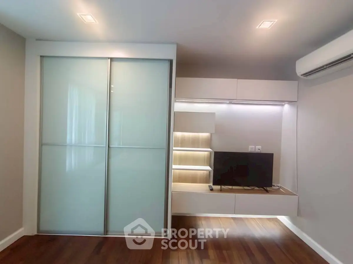 Modern living room with sleek built-in TV unit and sliding door wardrobe.