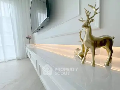 Elegant living room with modern decor and stylish TV setup, featuring chic gold deer sculptures and soft ambient lighting.