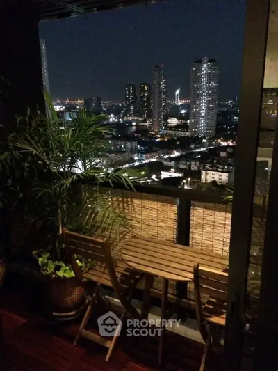 Stunning cityscape view from a cozy balcony with wooden furniture at night.