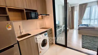 Modern apartment with sleek kitchen and cozy bedroom, featuring a washing machine and open layout.