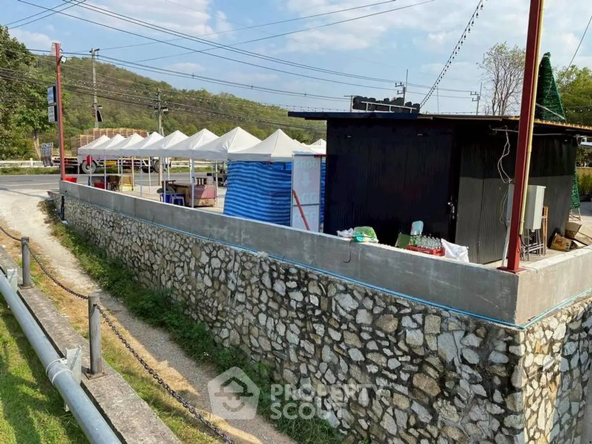 Charming roadside property with stone wall and outdoor tents, ideal for market or events.