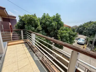 Spacious balcony with scenic view of lush greenery and residential street.