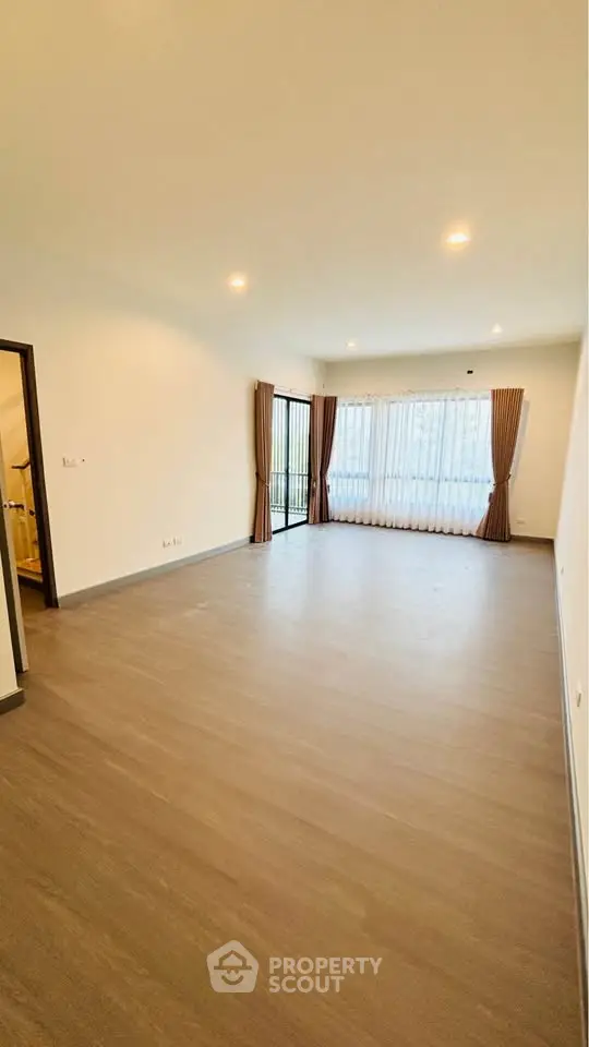 Spacious living room with large windows and elegant curtains, perfect for natural light and modern living.