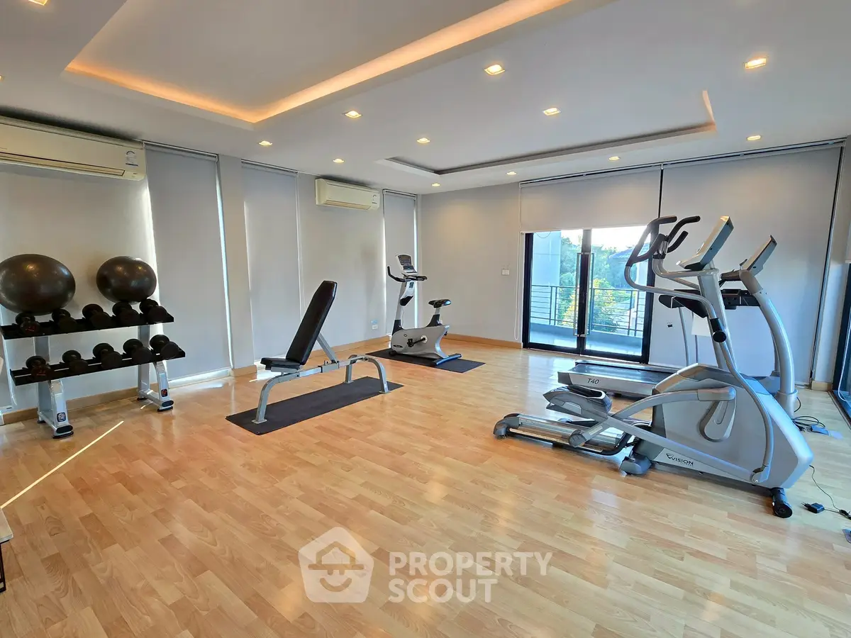 Spacious modern gym with exercise equipment and large windows for natural light.