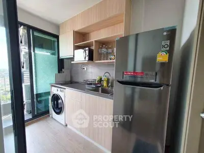 Modern kitchen with washing machine and stainless steel fridge in a sleek apartment.
