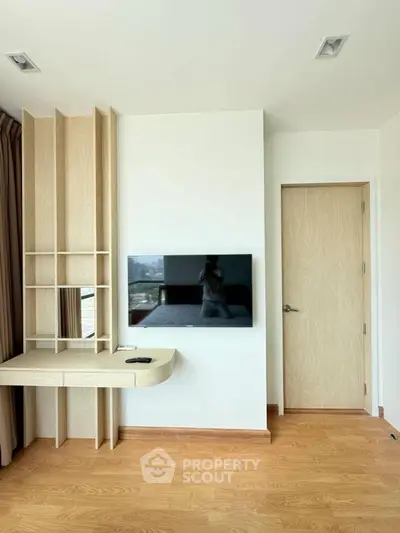 Modern bedroom with wall-mounted TV and stylish wooden desk in a bright apartment.