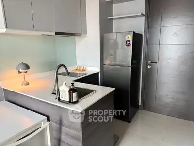 Modern kitchen with sleek design, featuring stainless steel fridge and stylish lighting.