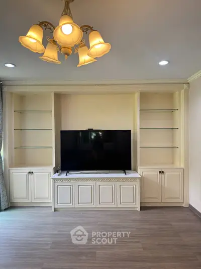 Elegant living room with built-in shelves and modern TV setup, featuring stylish lighting and wood flooring.