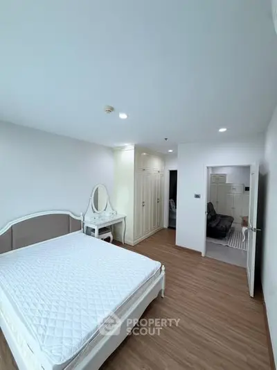 Spacious bedroom with elegant furniture and ample natural light, featuring a stylish vanity and built-in wardrobe.