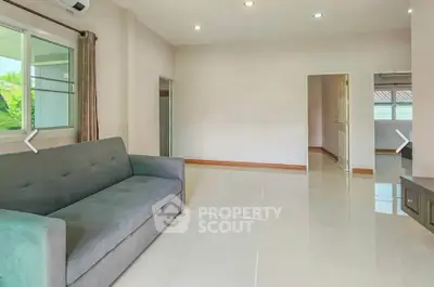 Spacious living room with modern sofa and large windows offering natural light.