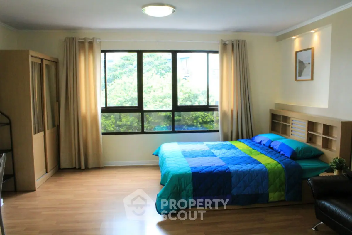 Spacious bedroom with large window and modern decor