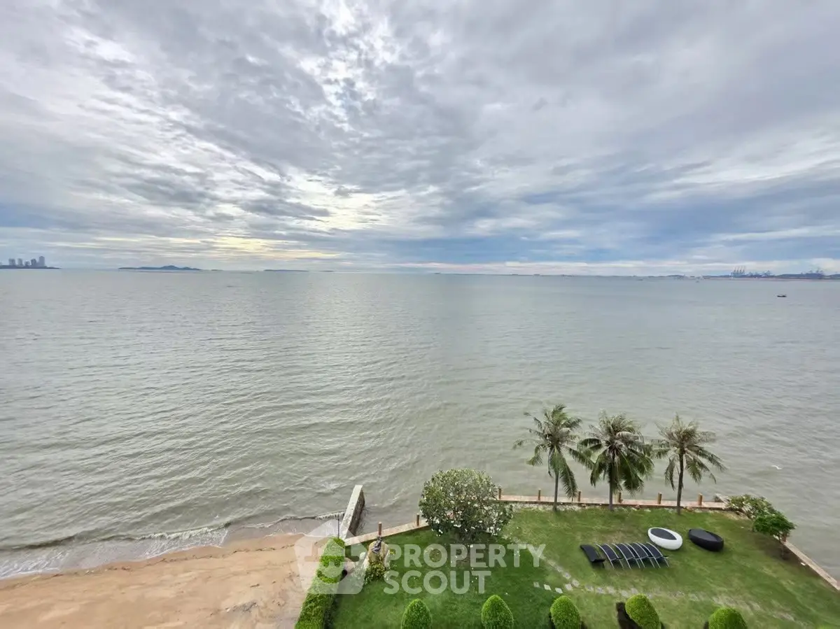 Stunning ocean view from a beachfront property with lush garden and palm trees.