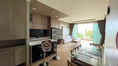 Modern open-plan living room with kitchen and dining area, featuring large windows and natural light.