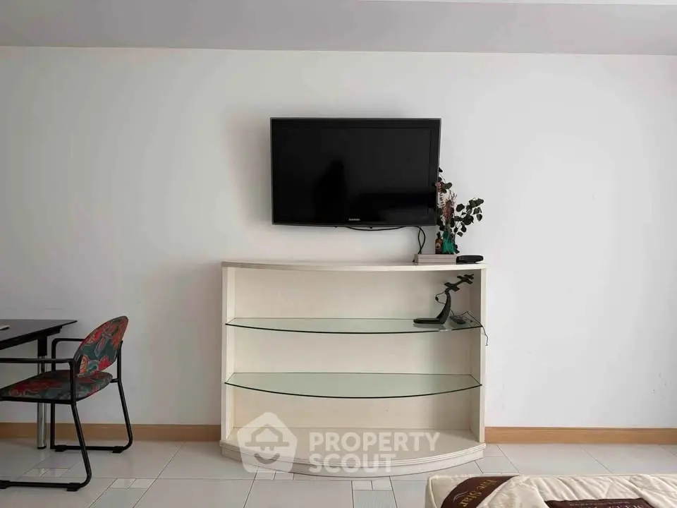 Modern living room with wall-mounted TV and sleek glass shelf unit.
