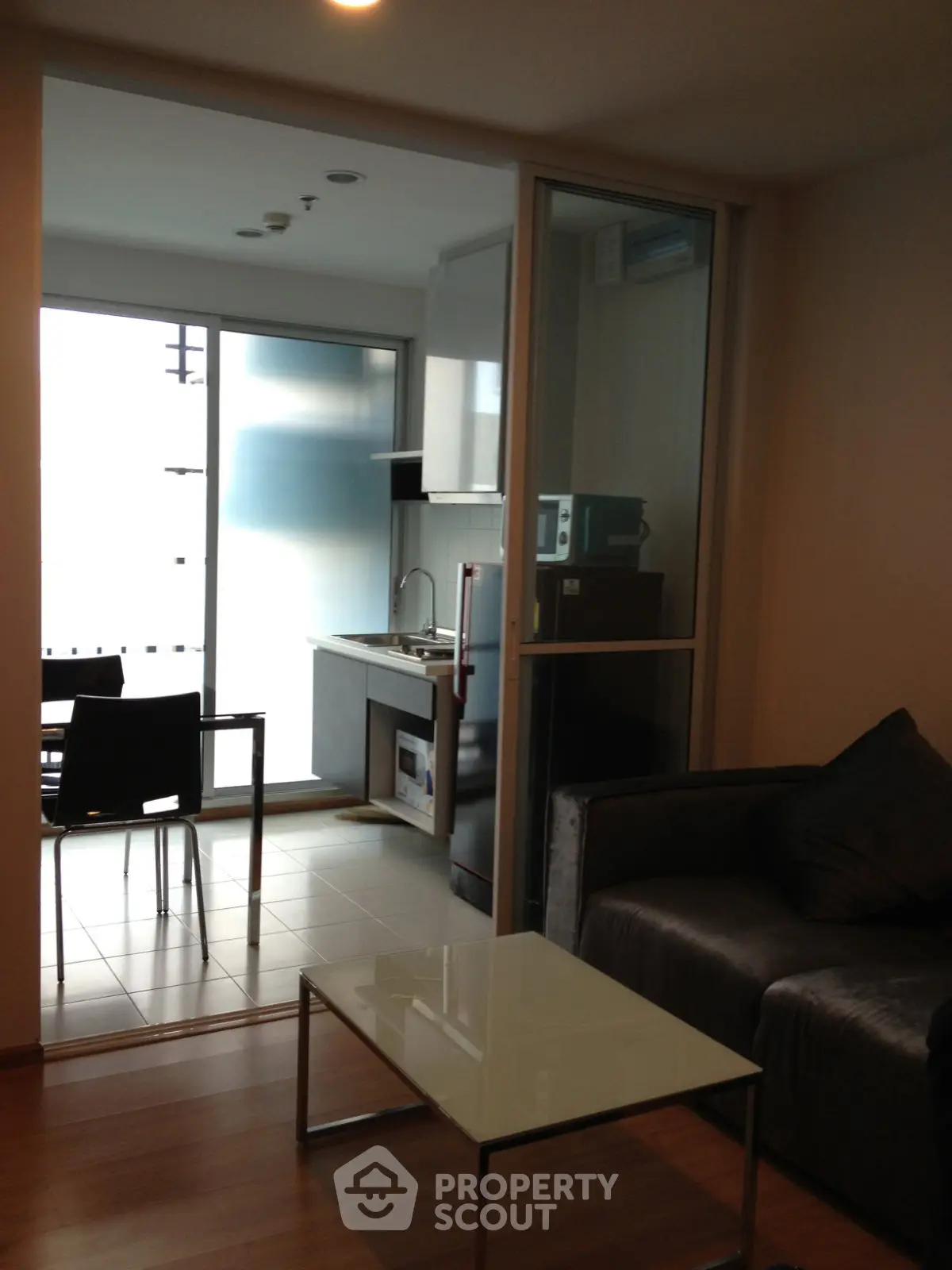 Modern apartment with open kitchen and cozy living area, featuring sleek furniture and natural light.