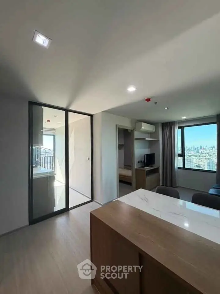 Modern apartment interior with open layout and city view, featuring sleek kitchen and spacious living area.