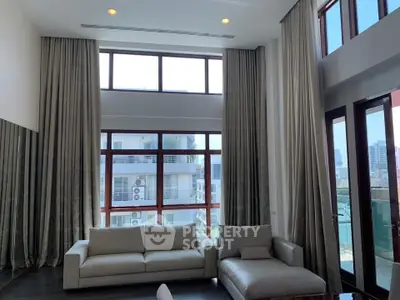 Spacious modern living room with high ceilings and large windows offering city views.