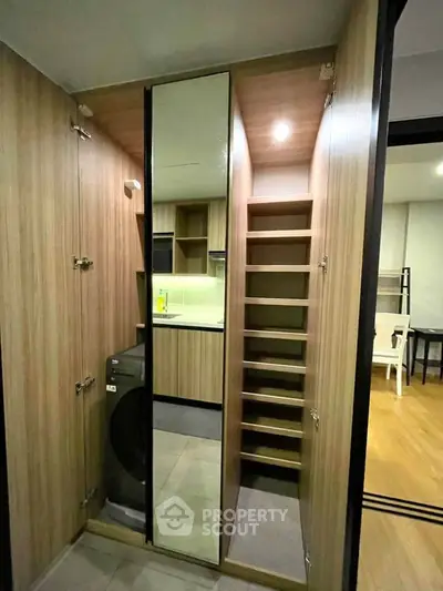 Modern apartment with sleek storage and laundry area, featuring wooden cabinetry and integrated washing machine.