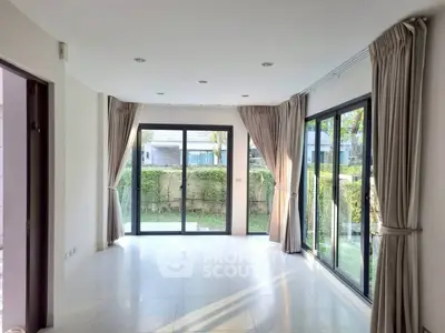 Spacious living room with large windows and garden view, perfect for natural light lovers.