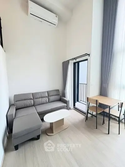 Modern living room with gray sofa, air conditioning, and balcony access in a bright apartment.