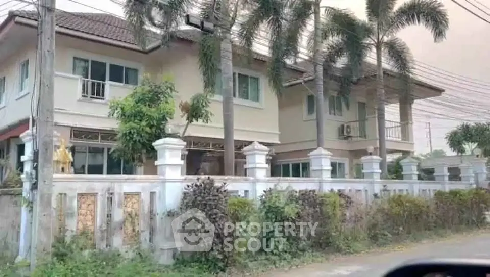 Charming two-story house with lush garden and palm trees, perfect for family living.