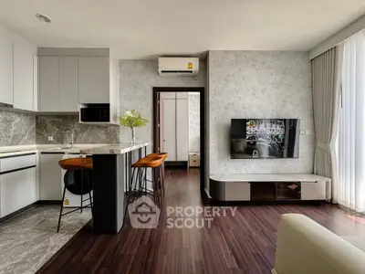 Modern living room with open kitchen, stylish decor, and sleek furniture in a contemporary apartment.