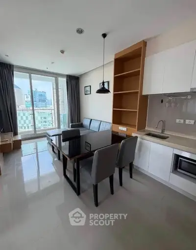 Modern living room with open kitchen and city view, featuring sleek furniture and ample natural light.