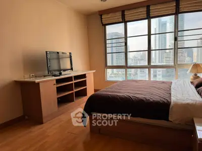 Spacious bedroom with city view and modern furnishings in a high-rise apartment.
