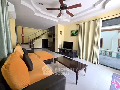 Spacious living room with modern decor and ceiling fan, featuring a cozy sofa and entertainment center.