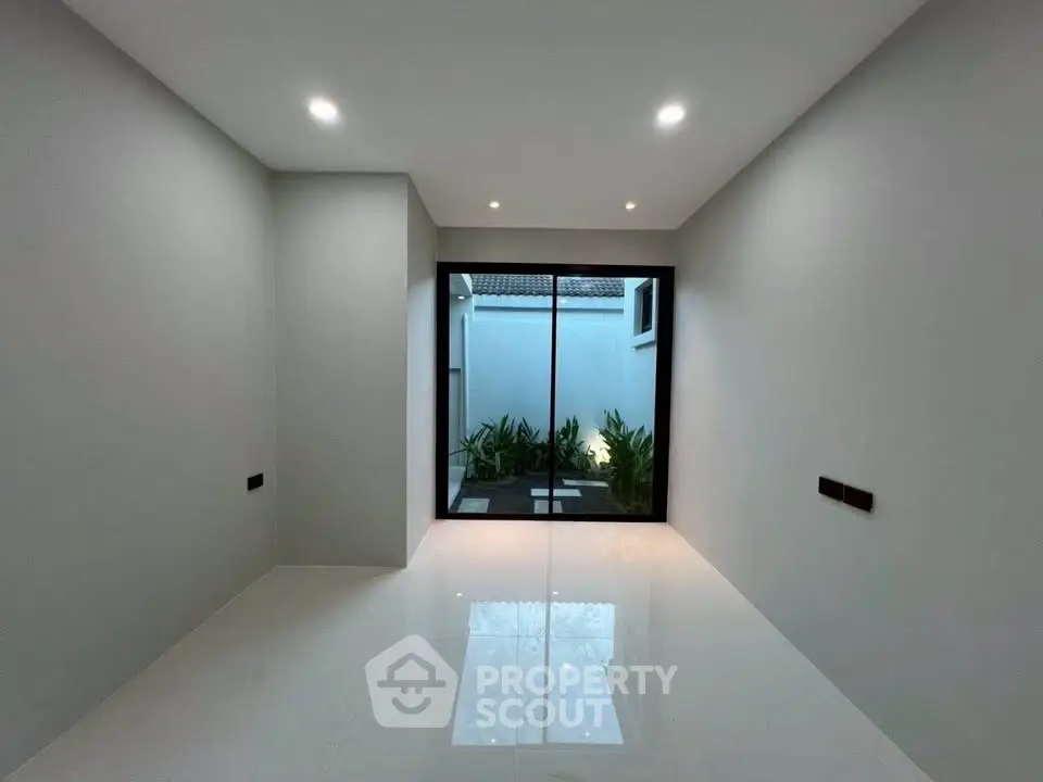 Spacious modern room with sliding glass doors leading to a small garden area.
