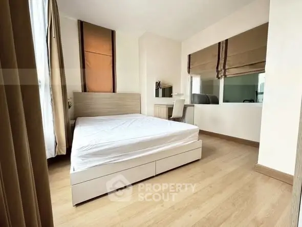 Spacious bedroom with modern decor and large window for natural light.