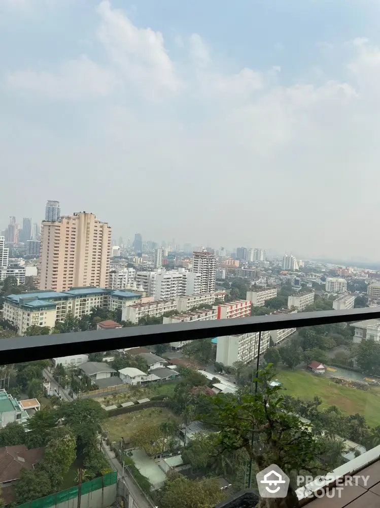 Stunning cityscape view from high-rise balcony with lush greenery and skyline