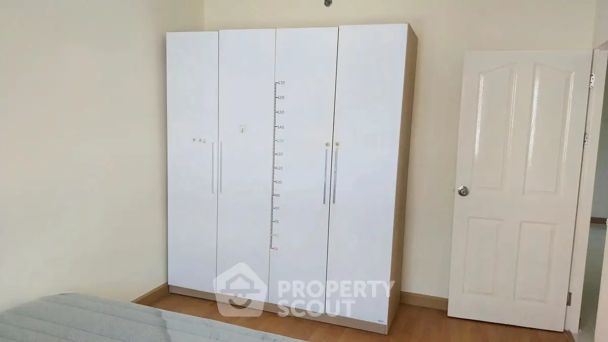 Spacious bedroom with modern white wardrobe and wooden flooring